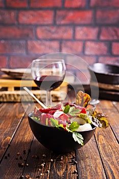salad with jamon and red wine on wooden table photo