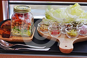 Salad in a Jar is layered with greens, with shredded carrots, chickpea, onion and tomato photo