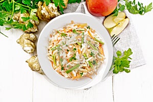 Salad of Jerusalem artichoke and apple in plate on light board top