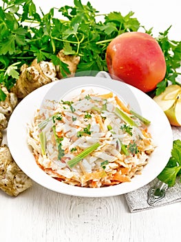 Salad of Jerusalem artichoke and apple in plate on wooden board