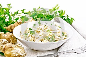 Salad of Jerusalem artichoke and eggs in plate on wooden table