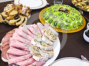 Salad with kiwi, ham, pieces of stuffed turkey, rolls with salmon at a Christmas dinner