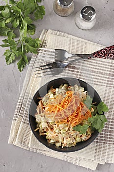 Salad with Korean carrots, meat and canned peas in a dark bowl on a gray background, Vertical format, Top view