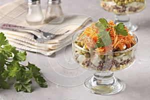 Salad with Korean carrots, meat and canned peas in transparent salad bowl a light gray background, Copy space