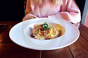 Salad in large plate and woman. Chicken meat, mushrooms, Korean-style carrots and potato. Closeup