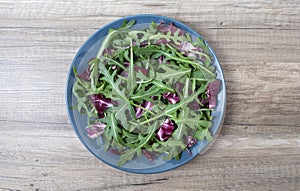 Salad leaves mix green, juicy snack, in a plate on a wooden table