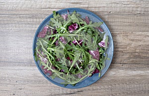 Salad leaves mix green, juicy snack, in a plate on a wooden table