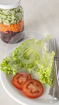 Plate of nutritious salad with lettuce and tomato and a glass with grated beetroot and carrot