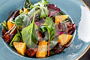 Salad with liver, arugula, orange, spinach and almonds on plate over dark stone surface. Healthy food concept. Top view