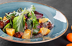 Salad with liver, arugula, orange, spinach and almonds on plate over dark stone surface. Healthy food concept. Top view