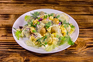 Salad with marinated mushrooms, eggs, red onion, boiled potato and mayonnaise on wooden table