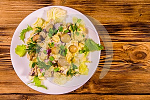 Salad with marinated mushrooms, eggs, red onion, boiled potato and mayonnaise on wooden table. Top view