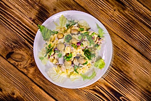 Salad with marinated mushrooms, eggs, red onion, boiled potato and mayonnaise on wooden table. Top view