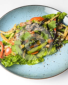 Salad mix with fresh vegetables asparagus and sesame seeds served on a blue plate. Lunch or dinner idea