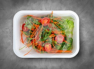 Salad mix (greens, carrots and cherry tomatoes). Healthly food. Takeaway food. Top view, on a gray background