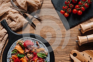 Salad with mussels, vegetables and jamon, fork with knife and fresh tomatoes