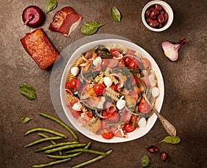 Salad with pasta, ham and vegetables in white bowl on gray stone backgroundtop view, copy space