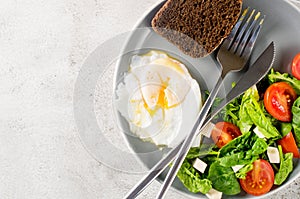 Salad in plate, egg, cup of coffee and croissant , fresh tulips in vase on clean white