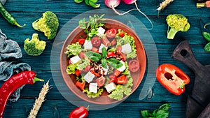 Salad in a plate. Feta cheese, cherry tomatoes, paprika, lettuce. Healthy food. On a blue wooden table table.
