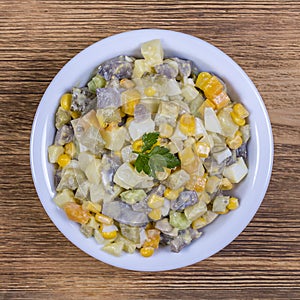 Salad of potato, mushrooms, cucumber, onion, carrot and corn in plate. Close up