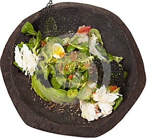 Salad with red caviar and crab in black wooden bowl isolated on whaite background