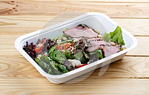 Salad with roast beef sous-vide. Healthy food. Takeaway food. On a wooden background