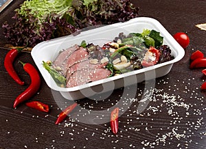 Salad with roast beef sous-vide. Healthy food. Takeaway food. On a wooden background