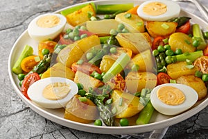 Salad with roasted potatoes, asparagus, boiled egg, tomato and peas closeup on the plate. Horizontal