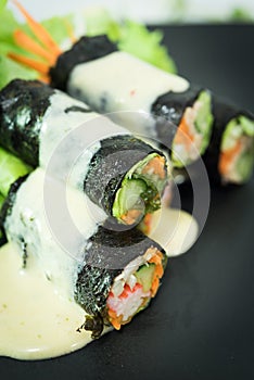 Salad roll in black dish ood with Crab Sticks, Cucumbers, Vegetables, Carrots sauce