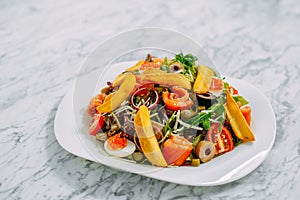 Salad with salmon, caviar, eggs and vegetables on a marble table