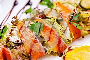 Salad with salmon, cucumber and mixed greens on white plate