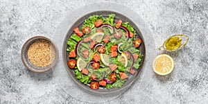 Salad with salmon, fresh vegetables and olive oil. Gray grunge background. Top view, flat lay. Banner.