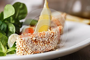 Salad with salmon grilled in sesame seeds, cherry tomatoes and quail egg on wooden table