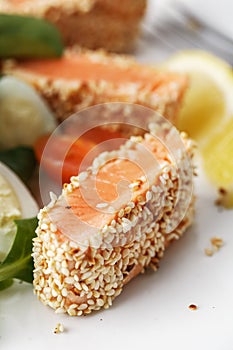 Salad with salmon grilled in sesame seeds, cherry tomatoes and quail egg on wooden table