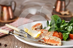 Salad with salmon grilled in sesame seeds, cherry tomatoes and quail egg on wooden table