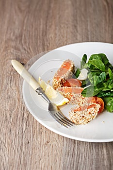 Salad with salmon grilled in sesame seeds, cherry tomatoes and quail egg on wooden table