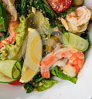 Salad with shrimp, cucumber, olives, tomatoes and basil. Glass of white wine. Place for text. Close up