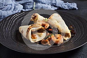 Salad with shrimp and pita bread. Seafood and vegetable on black ceramic plate.  Gourmet, restaurant healthy food concept. Dark