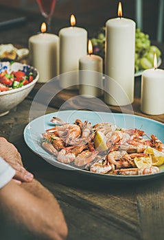 Salad, shrimps and candles on wooden table