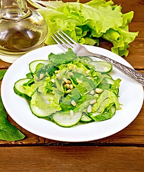 Salad from spinach and cucumbers with fork on wooden table