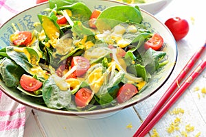 Salad with spinach, onions, tomatoes and a yellow turmeric dressing