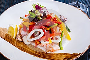 Salad with squid, bell pepper and onion on gray plate