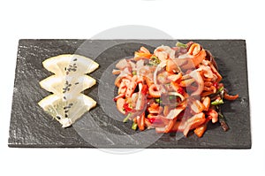 Salad with squid on a black plate with lemon