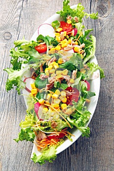 Salad with tomatoes and mais on wooden table
