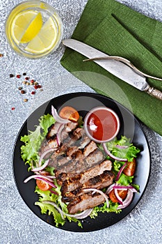 Salad with vegetables and grilled beef with tomato sauce