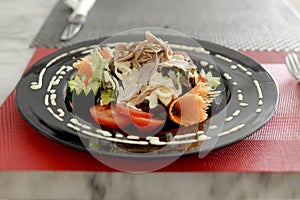 salad of vegetables,lechuga with mayonnaise,sliced meats of ham and jamon beautifully decorated with chopped vegetables on a plate