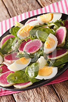 salad of watermelon radishes, eggs, spinach and lettuce mix close-up. vertical