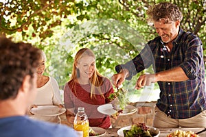 This salads all lettuce. A view of a family preparing to eat lunch together outdoors.