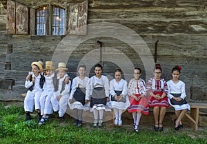 Salaj, Romania-May 13, 2018: Young girls and boys wearing traditional folk costumes in front of a old wooden church in the