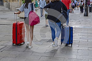 Closeup images of two woman taking a suitcase in city.